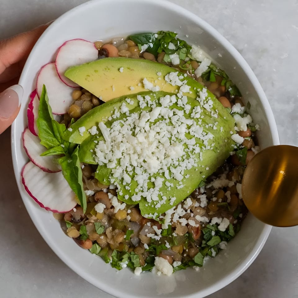 A healthy Kairos Jax lentil bowl with avocado, crumbled cheese, radishes, and herbs.